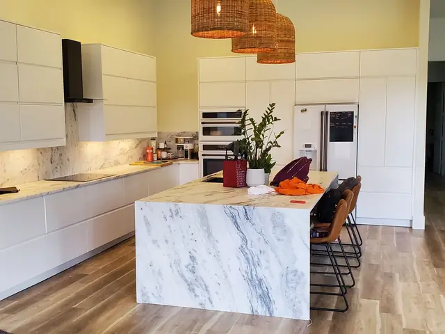 Handleless white kitchen with a marble waterfall island