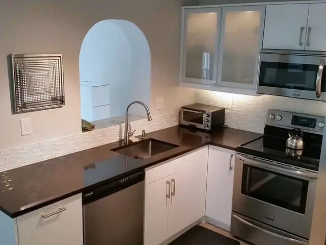 White IKEA kitchen with dark countertops and glass-front cabinets